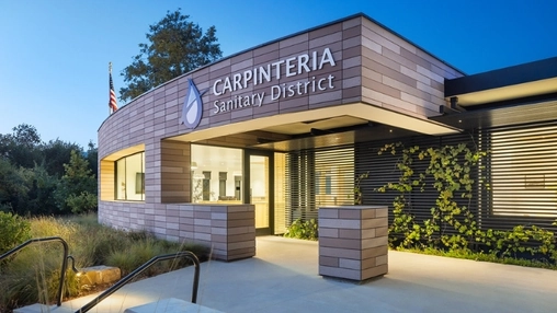 Carpinteria Sanitary District building entrance with modern cladding, warm lighting, and an American flag