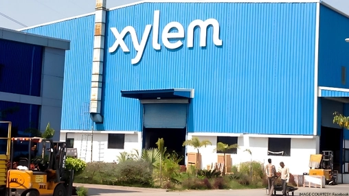 Blue corrugated industrial building exterior with Xylem branding above a rolling shutter door entrance