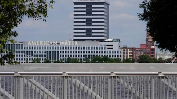 American Water branded building seen across a waterfront with a metal bridge railing in the foreground