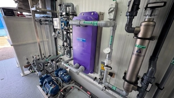 Industrial water treatment skid with purple tank, blue pumps, pipework, and a Gradiant branded heat exchanger